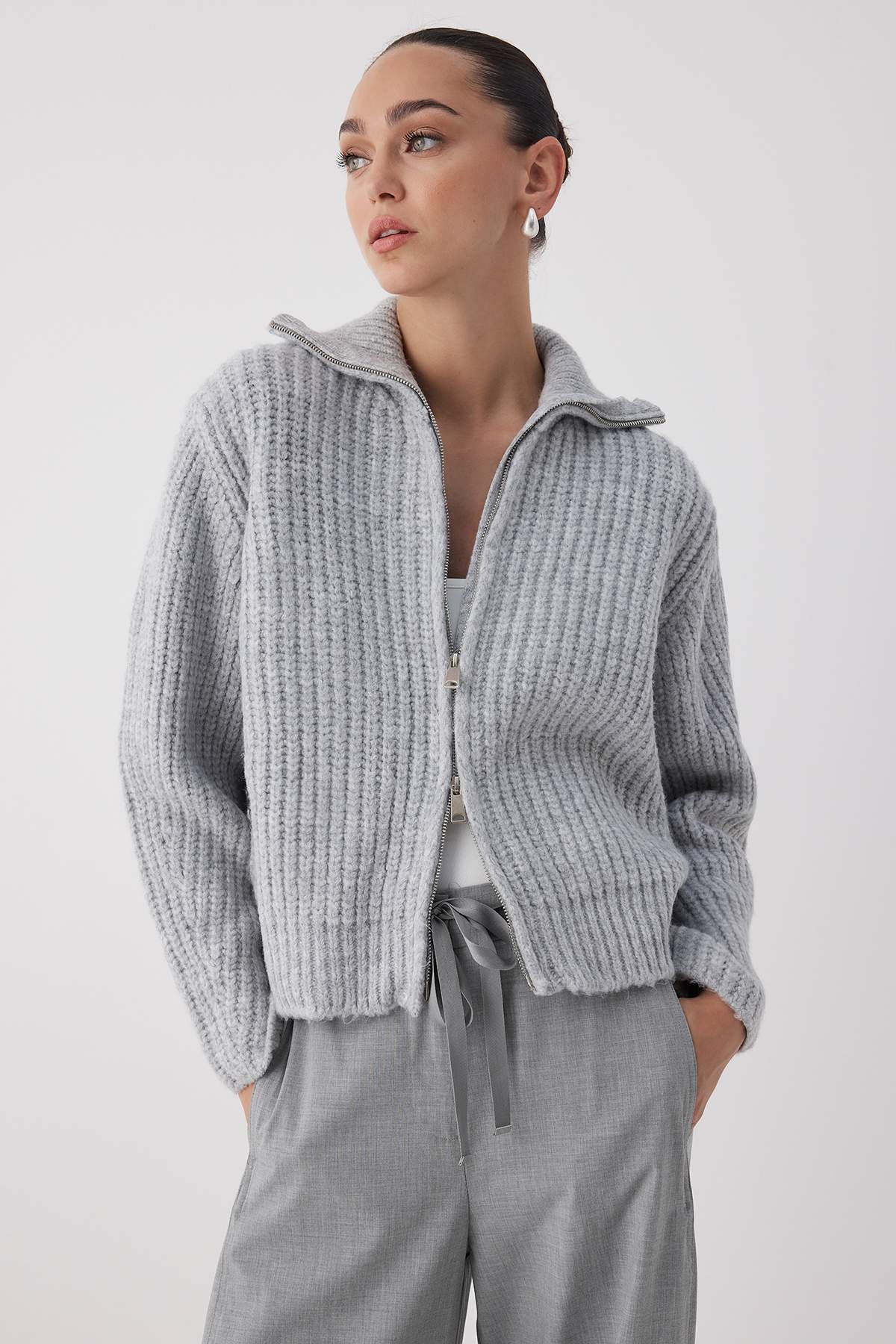  Woman wearing a light grey ribbed zip-up knit sweater with high collar and relaxed fit – AtikaStyle.”
