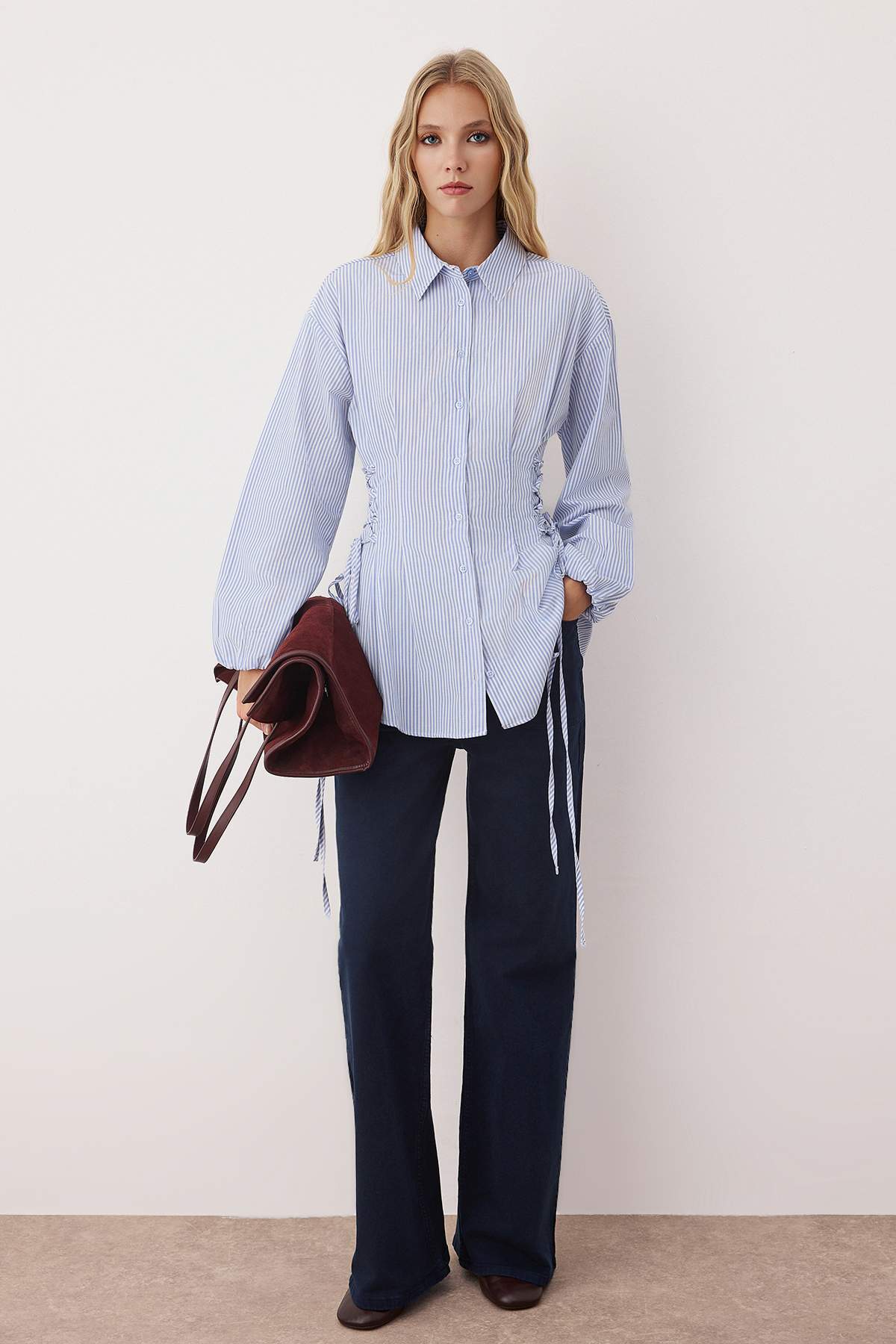 Woman wearing a blue striped button-up shirt with adjustable cinched waist ties – AtikaStyle.”
