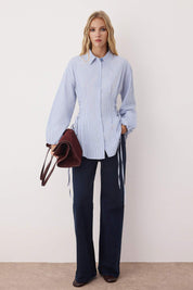  Woman wearing a blue striped button-up shirt with adjustable cinched waist ties – AtikaStyle.”
