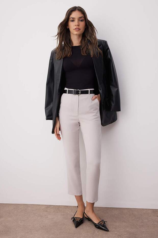 Woman wearing Atikastyle slim-fit beige tailored trousers – high waist ankle-length pants styled with black top and flats.”
