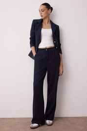 Woman wearing a navy suit with a white top against a plain background