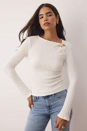 	•	Woman wearing white textured long sleeve top with gold accent – AtikaStyle casual chic blouse
	•	Close-up of gold accent detail on white textured blouse – AtikaStyle
	•	White textured long sleeve top styled with denim jeans – AtikaStyle
