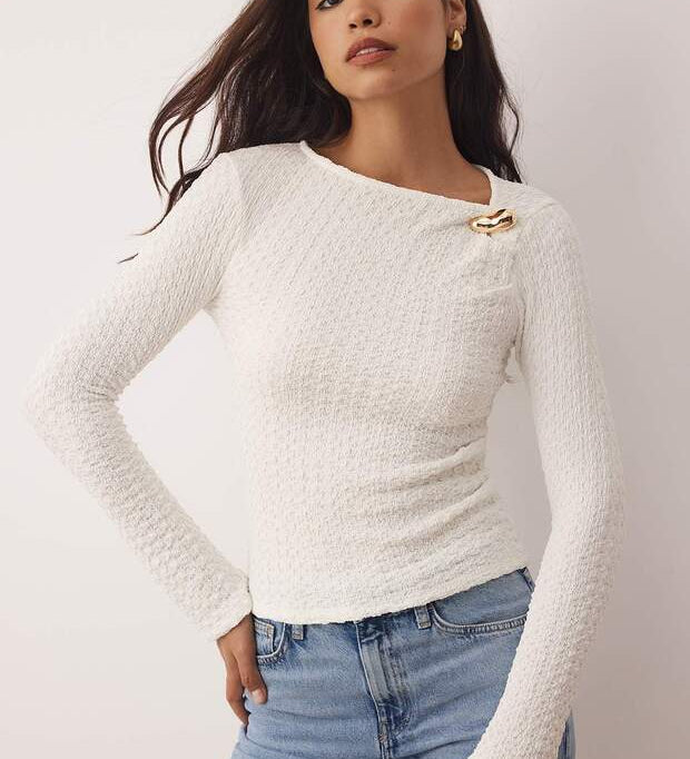 	•	Woman wearing white textured long sleeve top with gold accent – AtikaStyle casual chic blouse
	•	Close-up of gold accent detail on white textured blouse – AtikaStyle
	•	White textured long sleeve top styled with denim jeans – AtikaStyle
