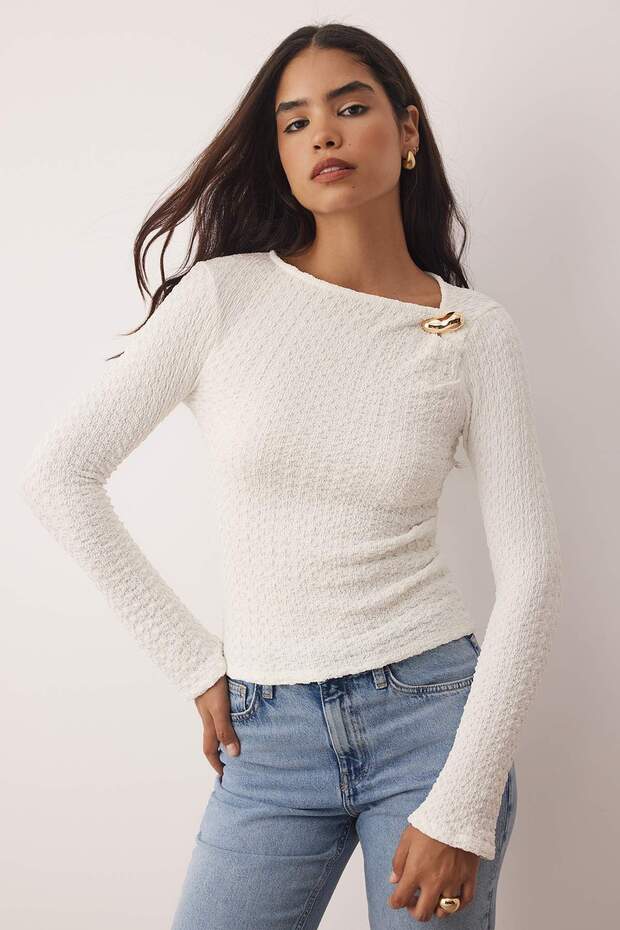 	•	Woman wearing white textured long sleeve top with gold accent – AtikaStyle casual chic blouse
	•	Close-up of gold accent detail on white textured blouse – AtikaStyle
	•	White textured long sleeve top styled with denim jeans – AtikaStyle
