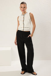 atikastyle knit vest, sleeveless cardigan, gold button top, chic office style, black and white layering piece, trendy knitwear 2025