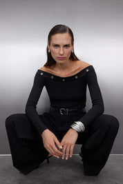 Turn heads in this black off-shoulder top with silver grommet details. A fitted, modern design perfect for nights out, parties, or chic layering. Made in Turkey.