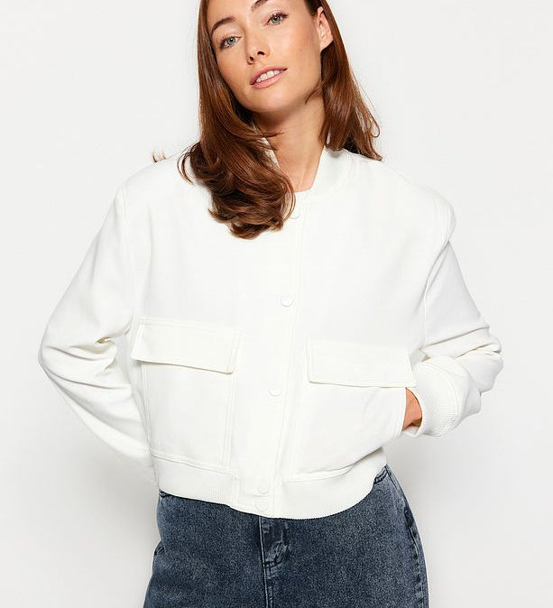 Woman wearing Atikastyle white bomber jacket with oversized front pockets, styled with jeans – casual chic outerwear for women.”
