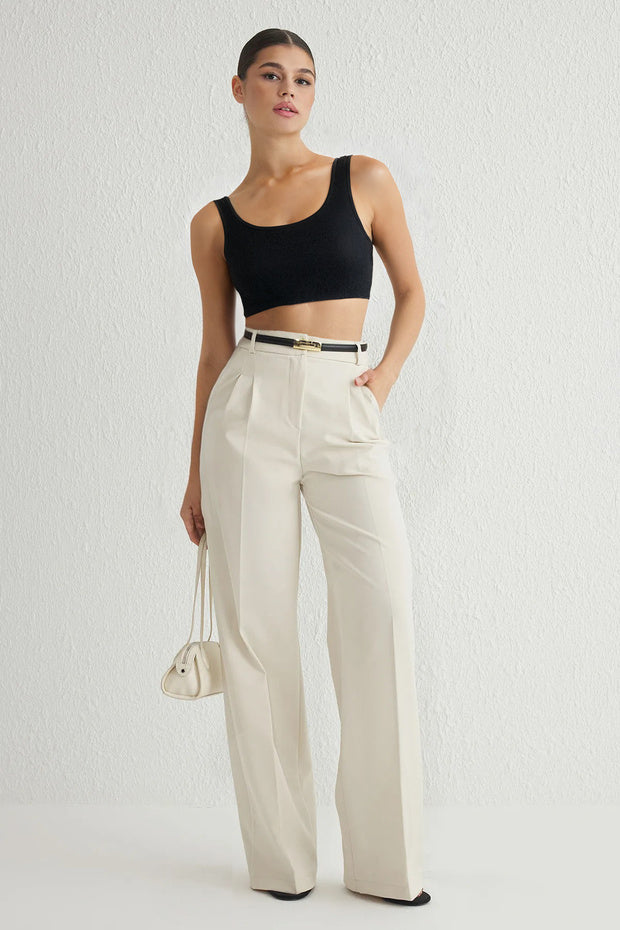 Woman wearing Atikastyle high-waisted beige wide-leg trousers with pleated front – elegant tailored workwear pants for women.”
