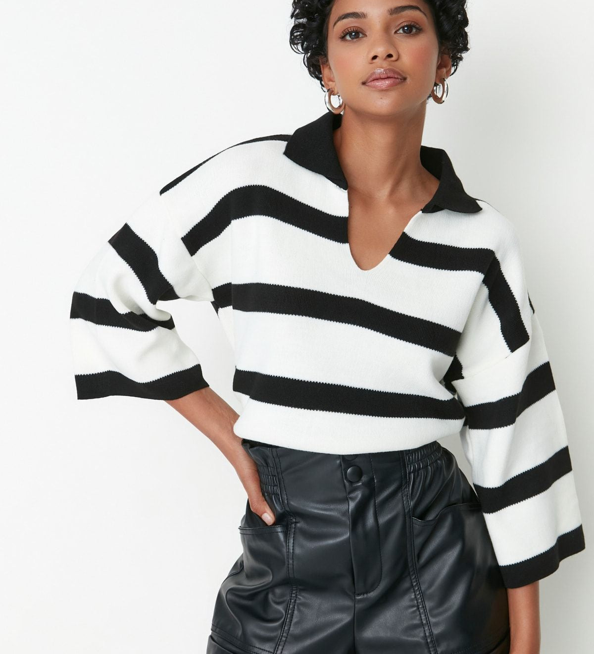 Woman wearing Atikastyle black and white striped knit polo sweater with deep V-neckline – casual chic long sleeve top.”

