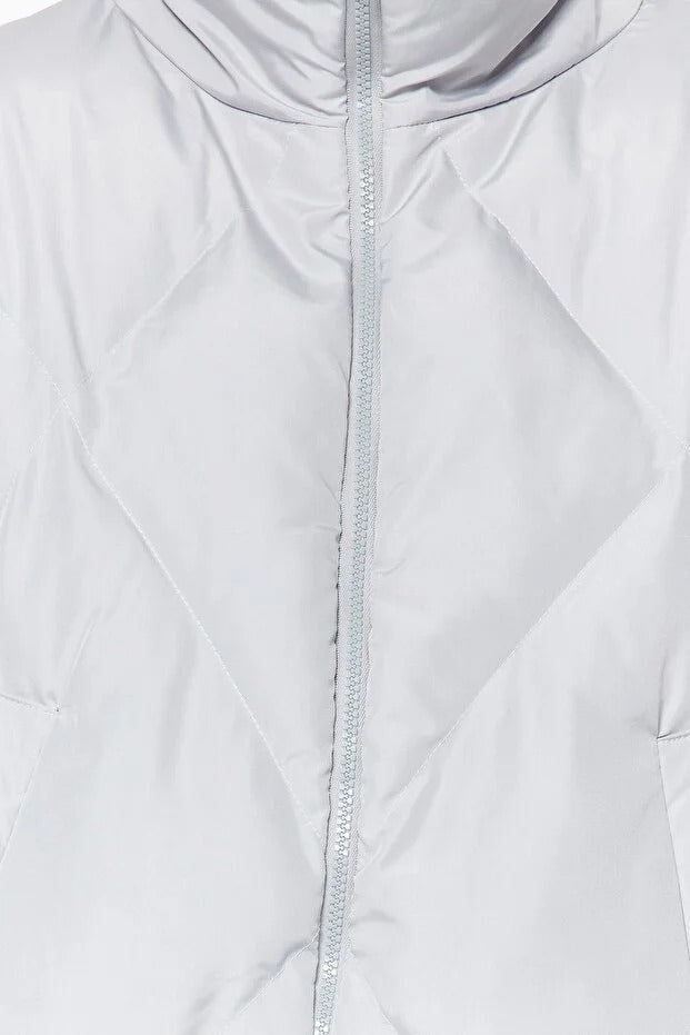 Close-up of a light gray quilted jacket with a zipper
