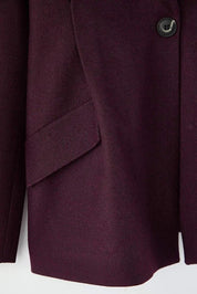 Close-up of a burgundy coat with a button on a white background