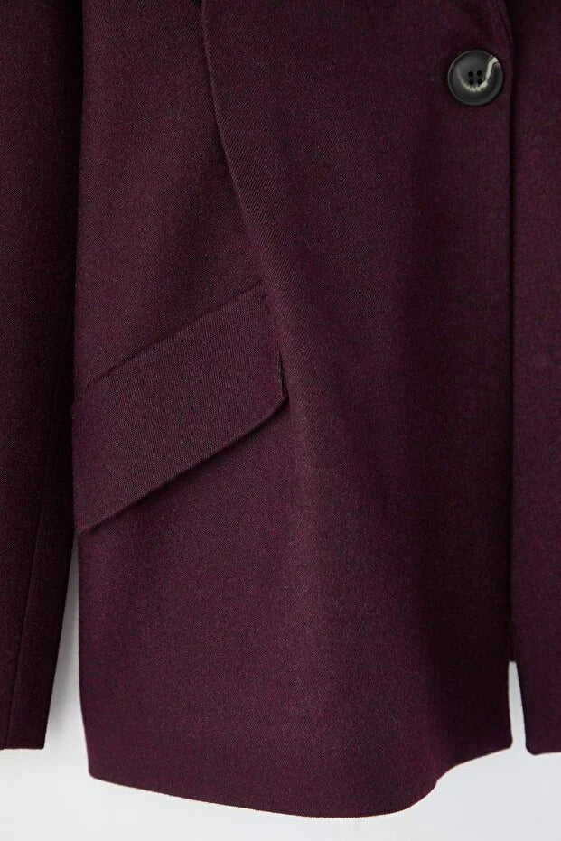 Close-up of a burgundy coat with a button on a white background