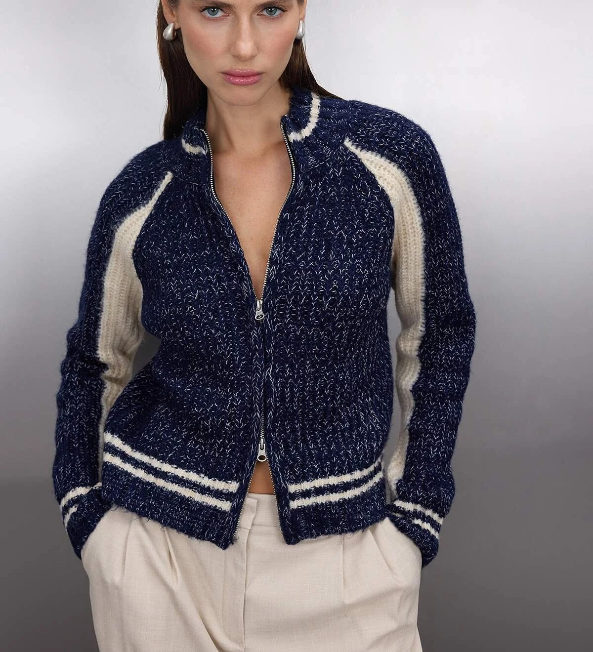 Woman wearing a navy and cream contrast knit zip-up sweater with ribbed sleeves and stripe hem – AtikaStyle.”
