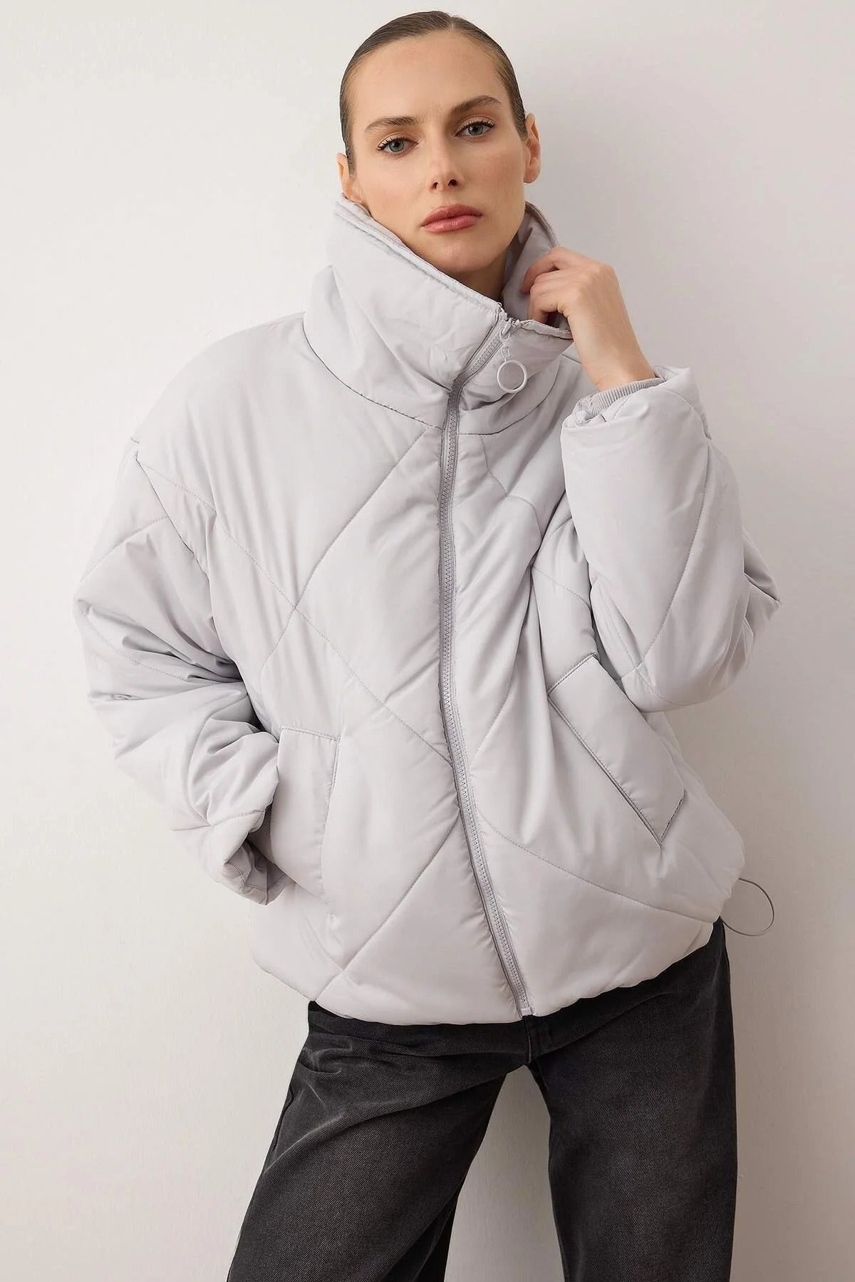 Person wearing a light gray quilted jacket against a plain background