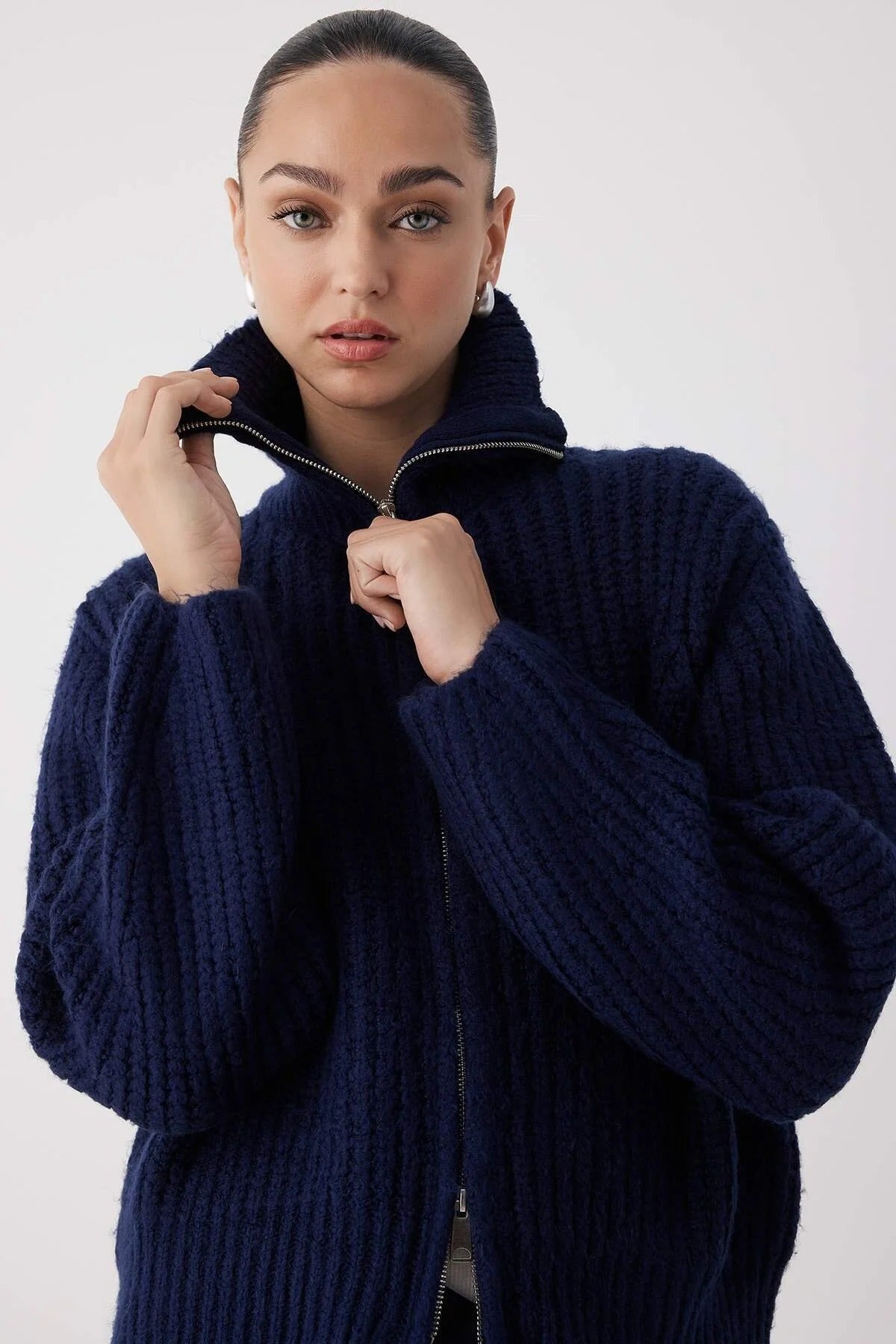 Woman wearing a navy blue ribbed sweater against a white background