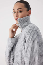 Woman wearing a gray knitted sweater against a light background