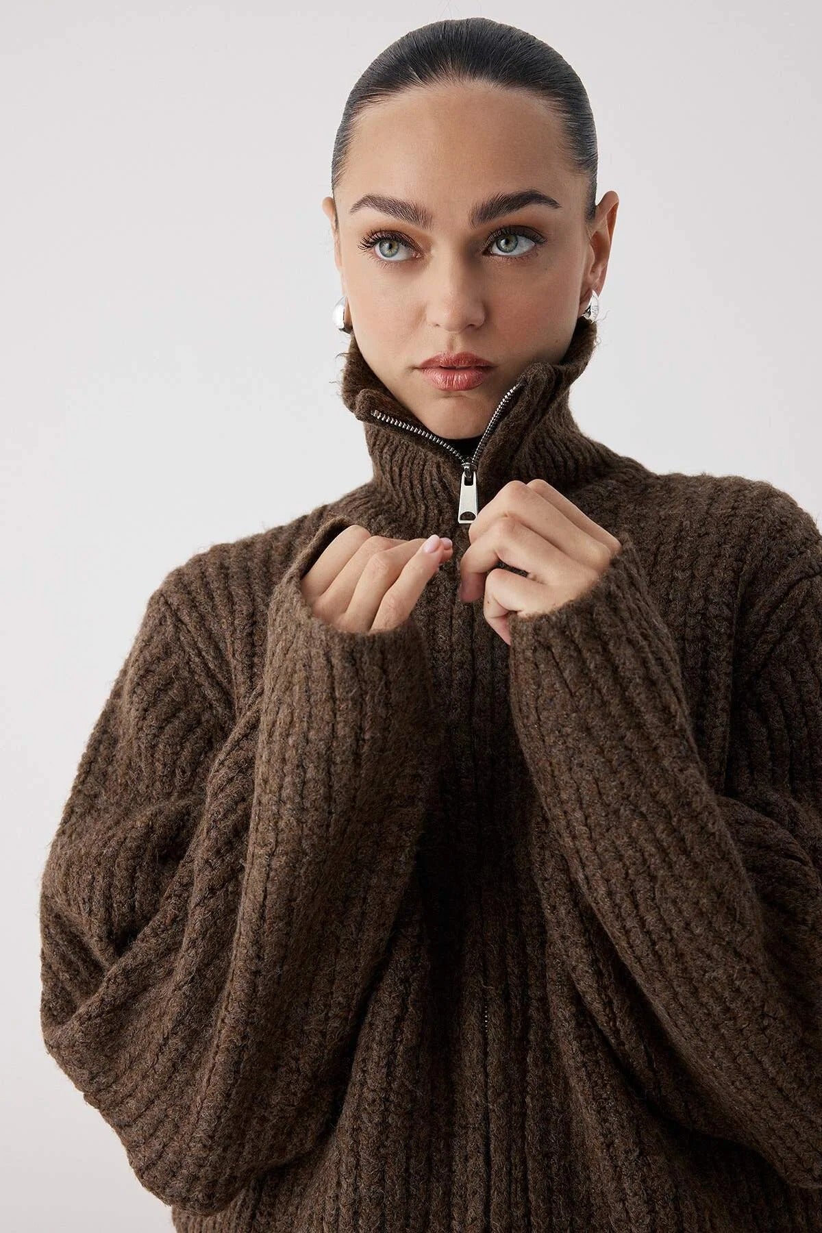 Woman wearing a brown knitted sweater against a plain background