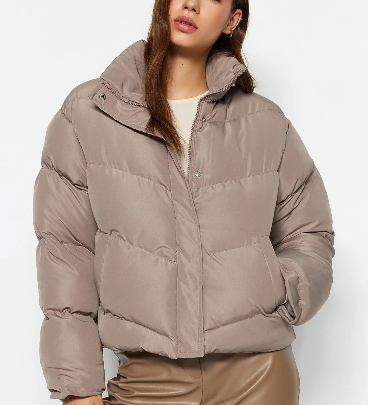 Woman wearing a beige puffer jacket and pants on a white background