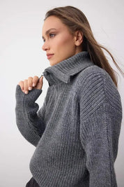 Woman wearing a grey chunky ribbed turtleneck sweater with a cozy high-neck fold-over design — AtikaStyle.”
