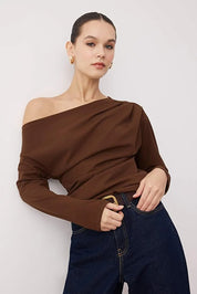 Woman wearing a chocolate brown off-shoulder long-sleeve top paired with dark denim — AtikaStyle.”
