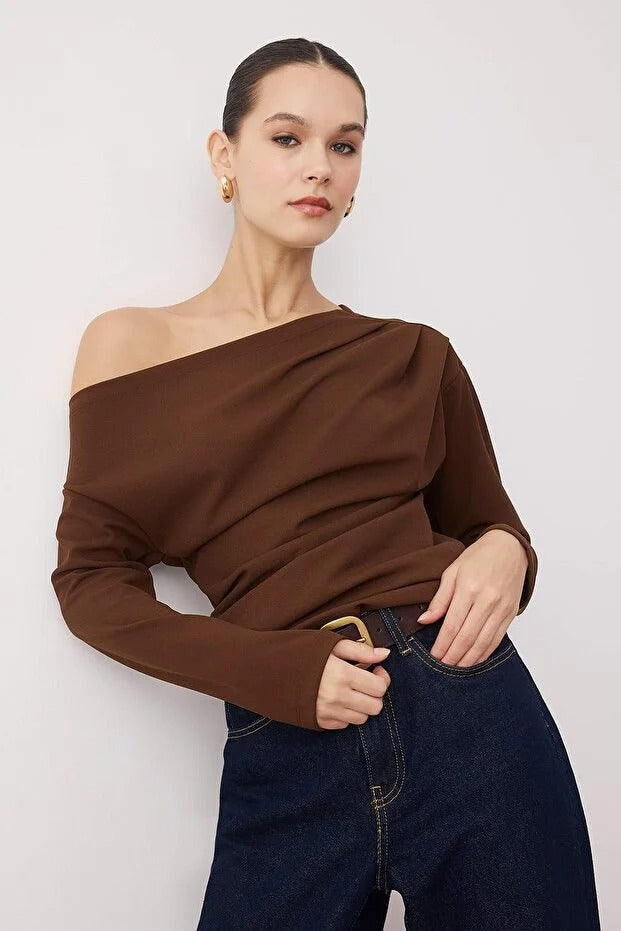 Woman wearing a chocolate brown off-shoulder long-sleeve top paired with dark denim — AtikaStyle.”
