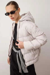 Person wearing a light gray puffer jacket with a plain background