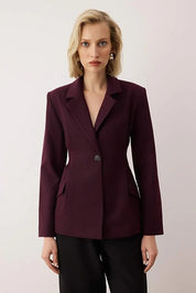 Woman wearing a burgundy blazer against a plain background