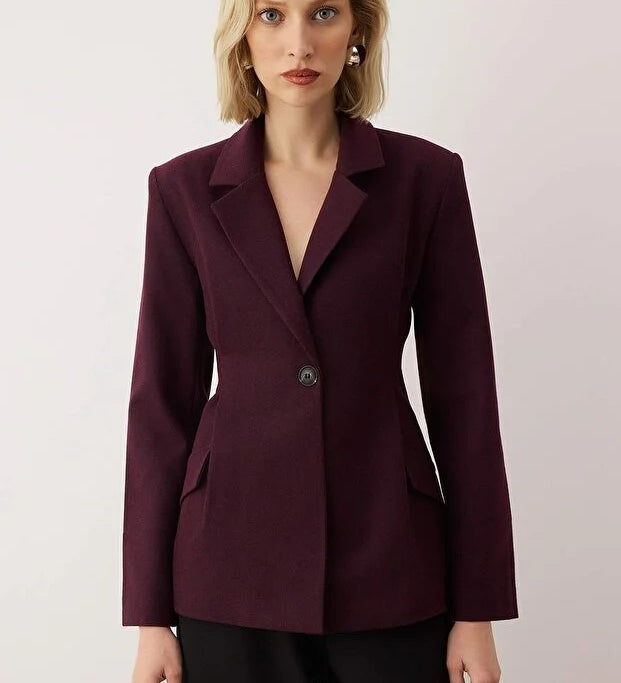Woman wearing a burgundy blazer against a plain background