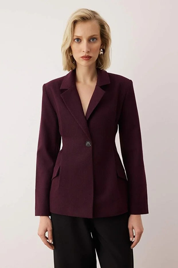 Woman wearing a burgundy blazer against a plain background