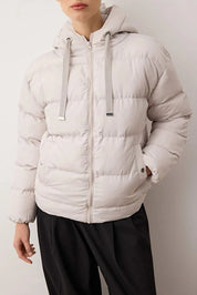 Person wearing a light gray puffer jacket against a plain background