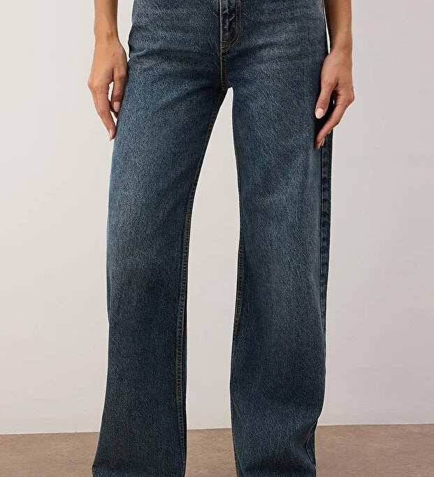 Person wearing blue jeans against a plain background