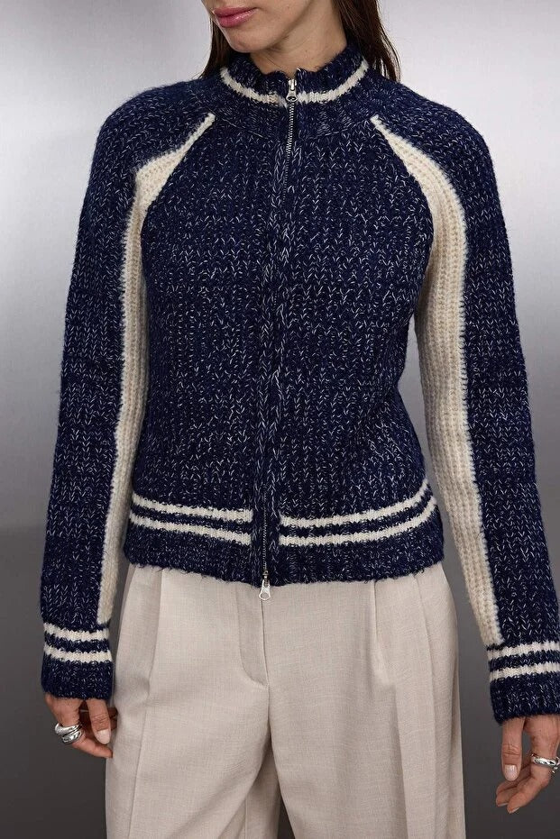 Navy blue and beige zip-up sweater worn by a person on a plain background