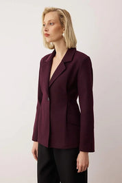 Woman wearing a burgundy blazer against a plain background