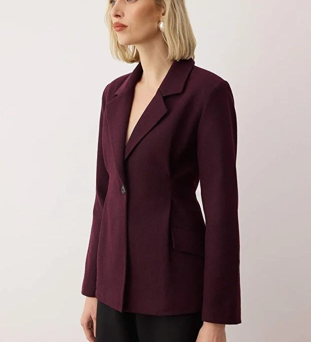 Woman wearing a burgundy blazer against a plain background
