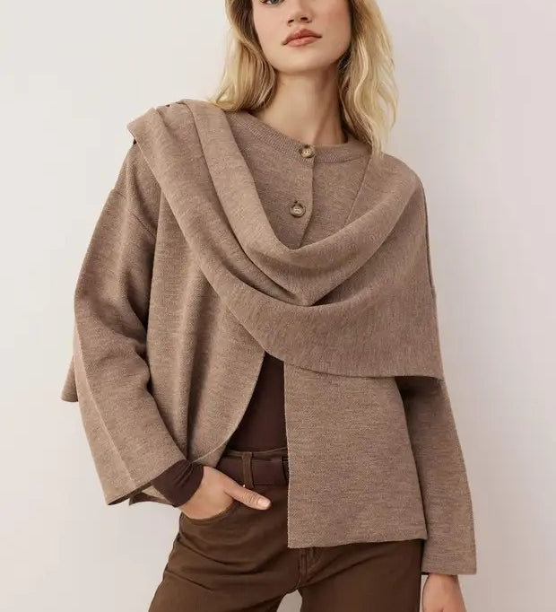 Woman wearing a brown poncho over a outfit against a plain background