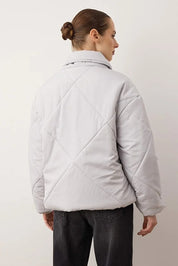Person wearing a light gray quilted jacket against a plain background