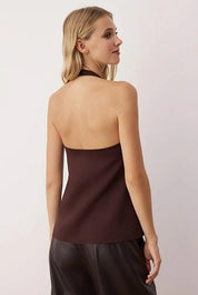 Woman wearing a brown halter top against a plain background