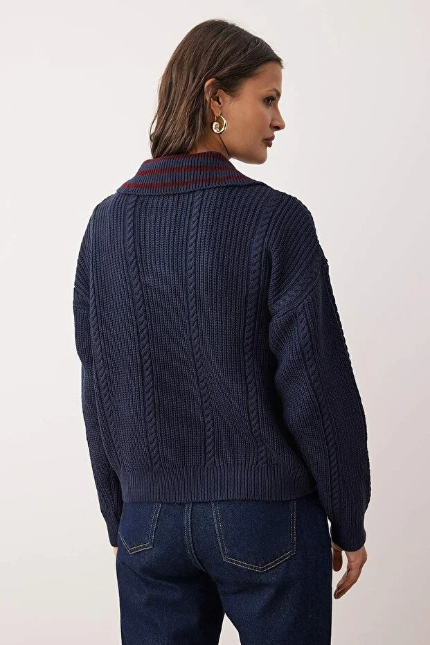 Person wearing a dark blue cable knit sweater with a white background