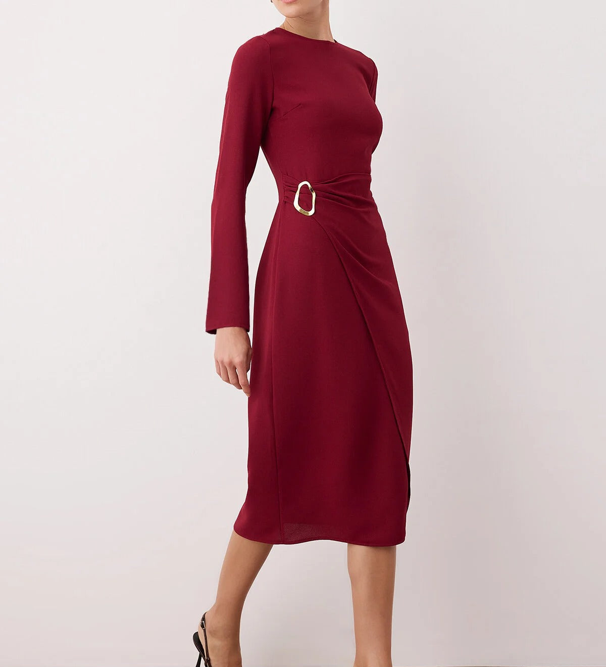 Woman wearing a burgundy dress with a belt on a plain background