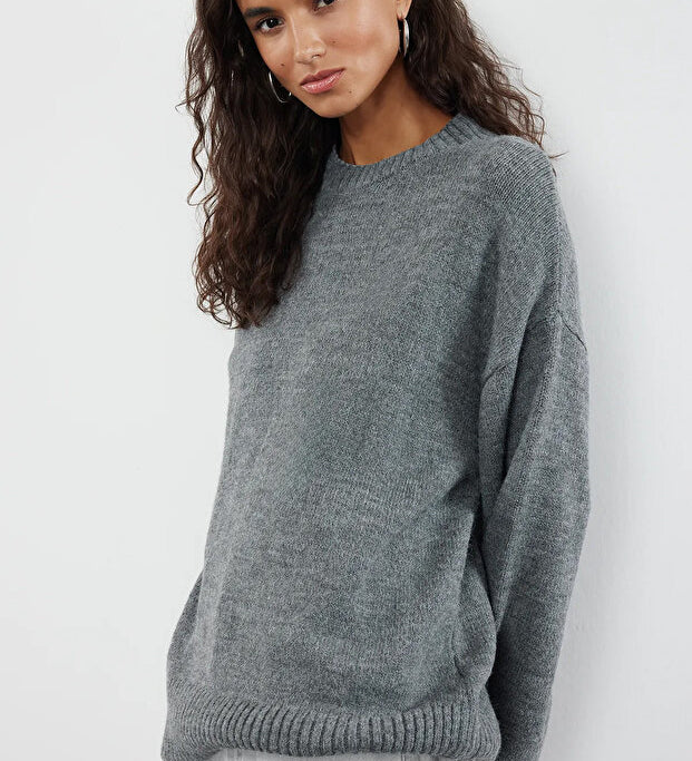 Woman wearing a gray sweater against a white background
