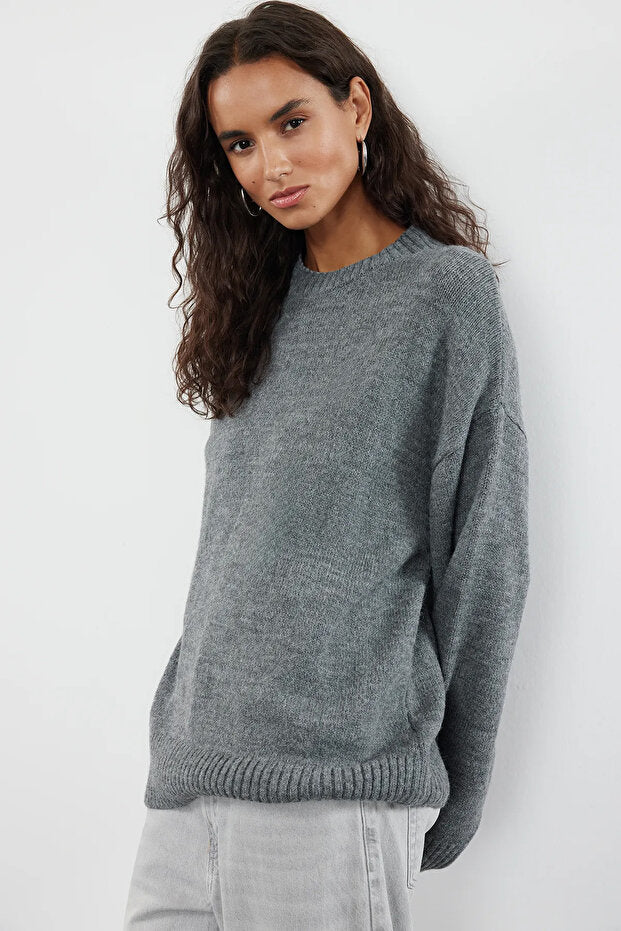 Woman wearing a gray sweater against a white background