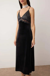 Woman wearing a black slip dress with lace details against a plain background