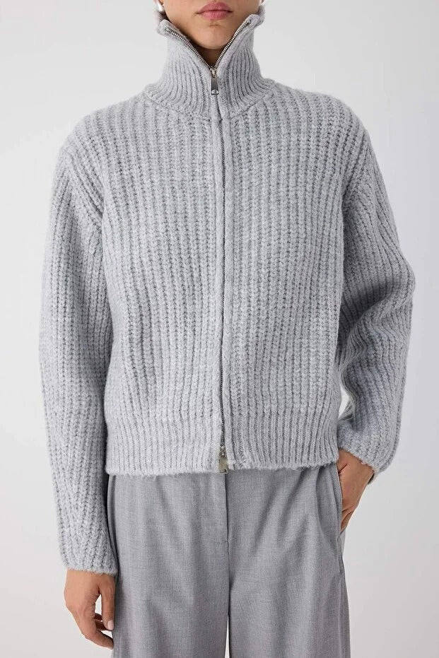 Person wearing a gray knitted sweater and pants on a white background