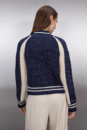 Woman wearing a navy and white striped sweater against a gray background