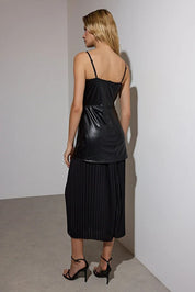 Woman wearing a black dress with pleated skirt against a plain background