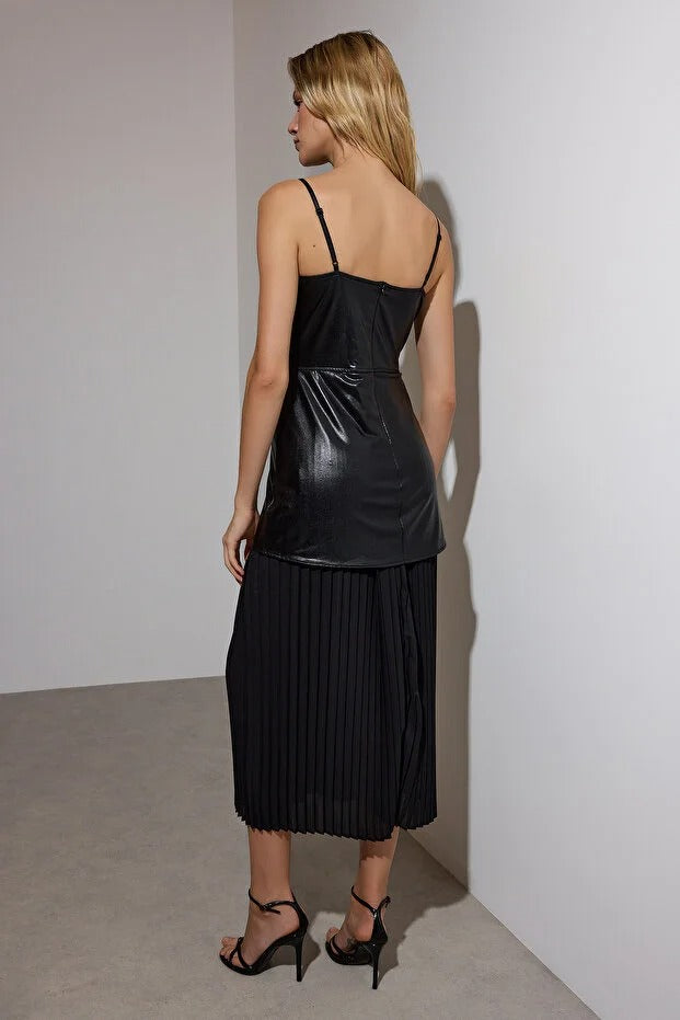 Woman wearing a black dress with pleated skirt against a plain background