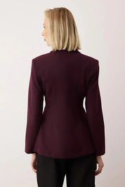 Person wearing a burgundy blazer against a light background