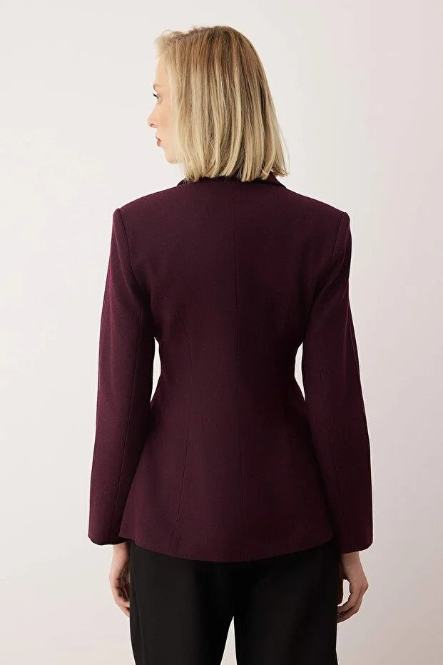 Person wearing a burgundy blazer against a light background