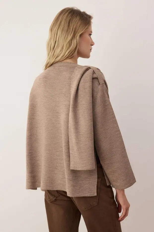 Woman wearing a brown cape over a plain background