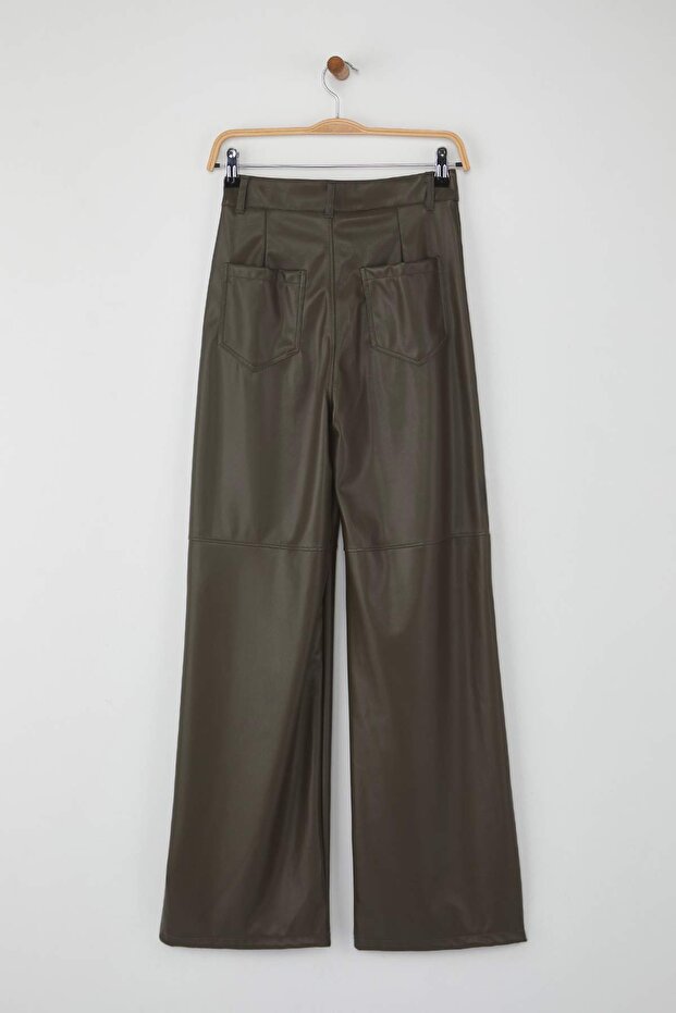 Green pants hanging on a wooden hanger against a white background